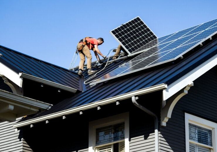 Two people on the roof of a home install solar panels.