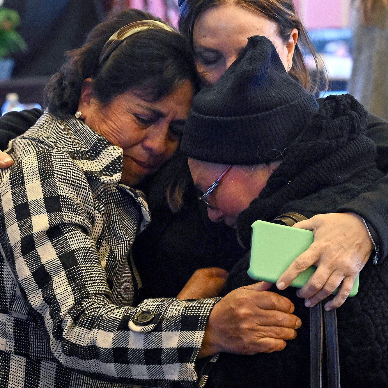 Three women share an emotional hug.