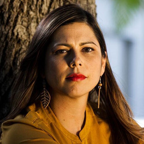 Laura Arroyo, looking directly at the camera, tree in the background.