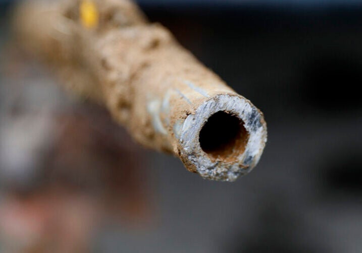 A close up picture of the open side of a dirty metal pipe that has been cut in half.