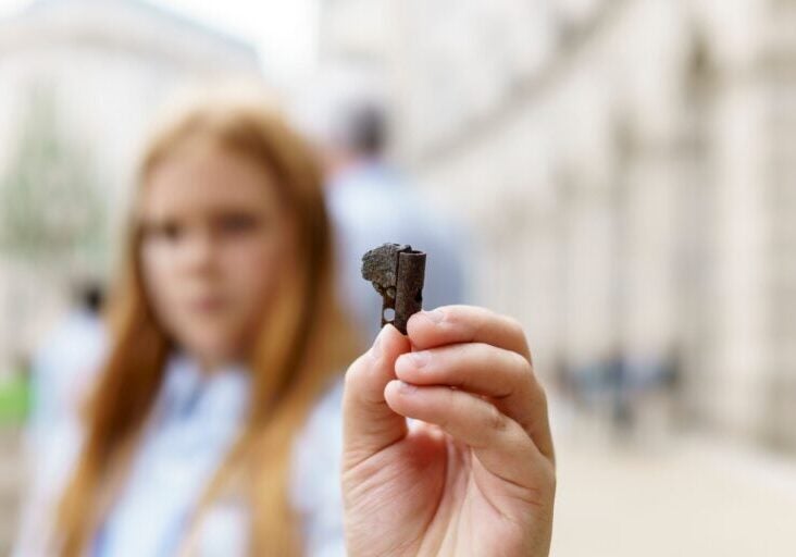 A youth scientist who asked the U.S. EPA to ban lead wheel weights holds up a fragmented part of a lead wheel weight found a block from the U.S. EPA building along Constitution Ave., in Washington D.C.