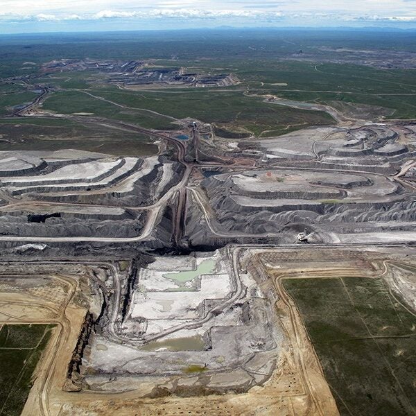An aerial view of North Antelope Mine in Wyoming's Powder River Basin shows a deep, expansive tiered pit. The pit is so large, machinery inside the pit is dwarfed by the walls.
