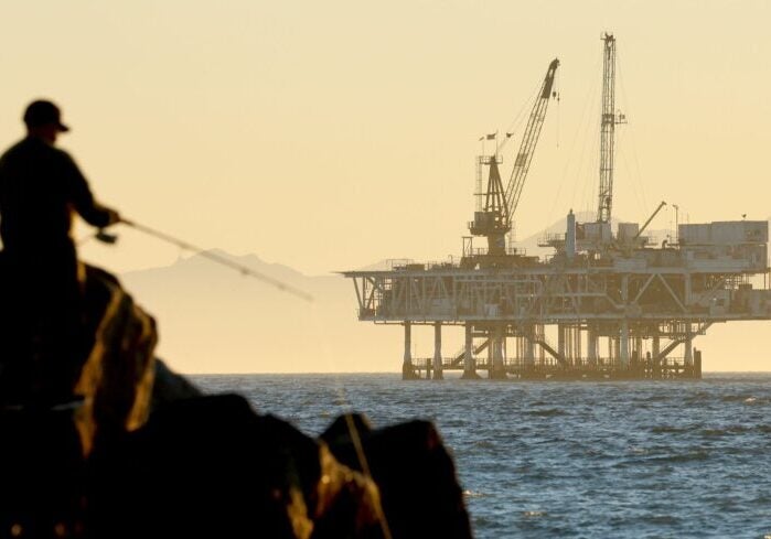 A person fishes with offshore oil and gas platform Esther in the distance on Jan. 5, 2025, in Seal Beach, California.