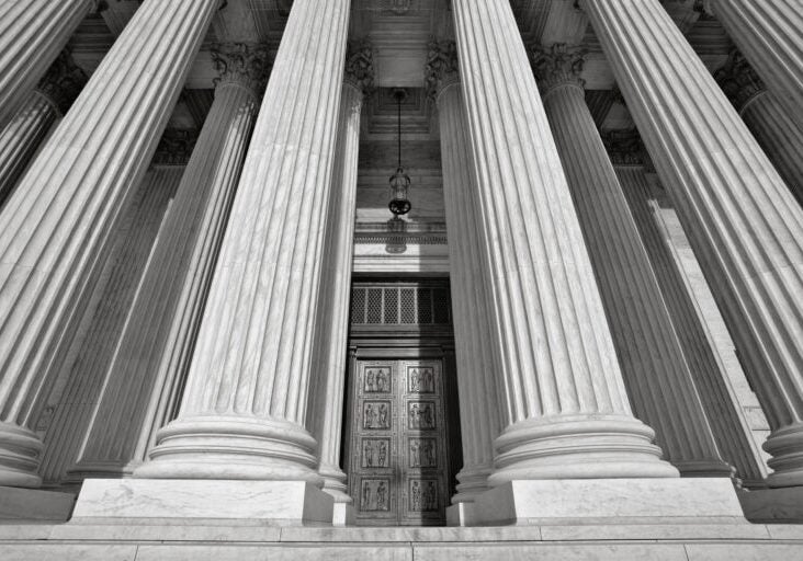 An upward view of the U.S. Supreme Court building near the top of the front steps.
