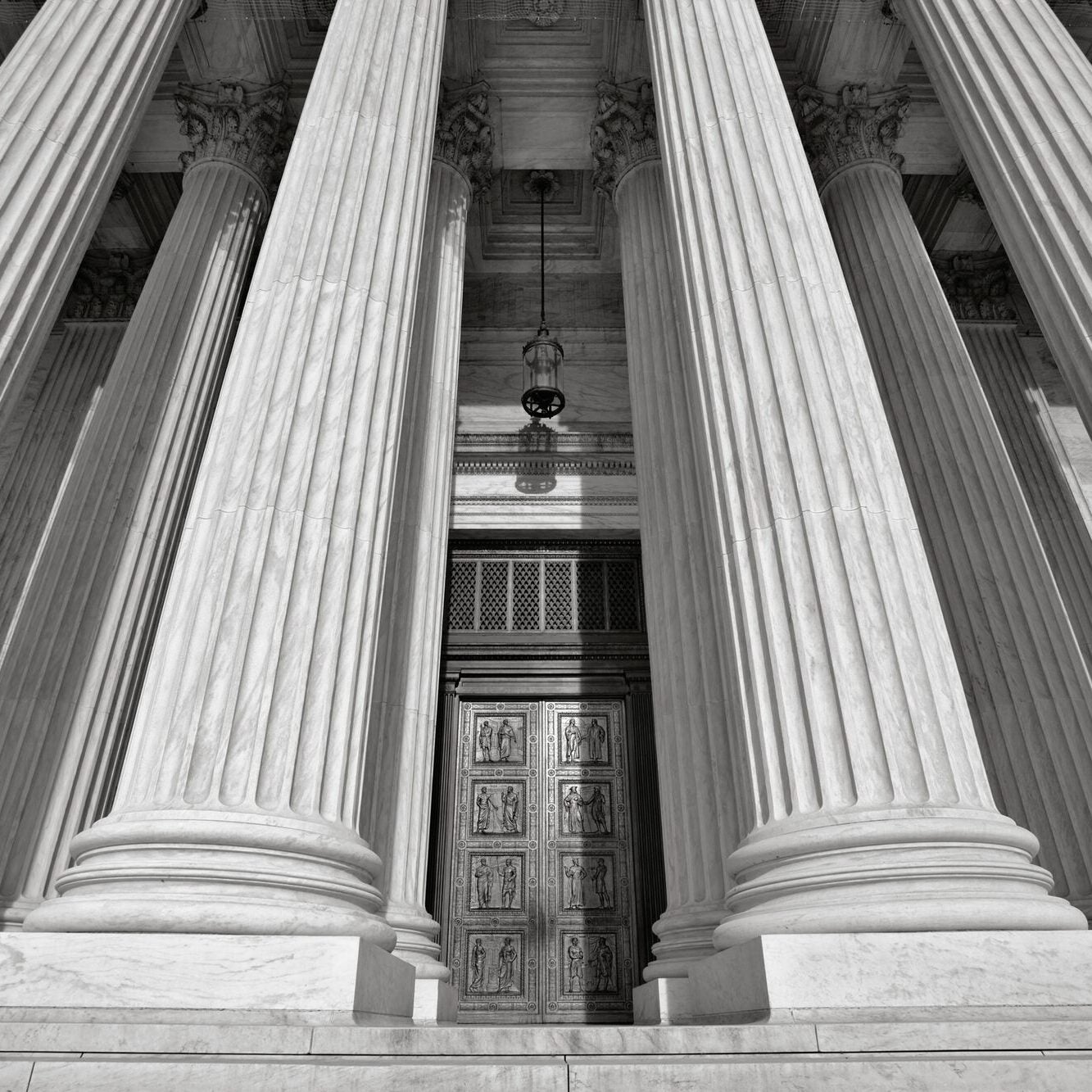 An upward view of the U.S. Supreme Court building near the top of the front steps.