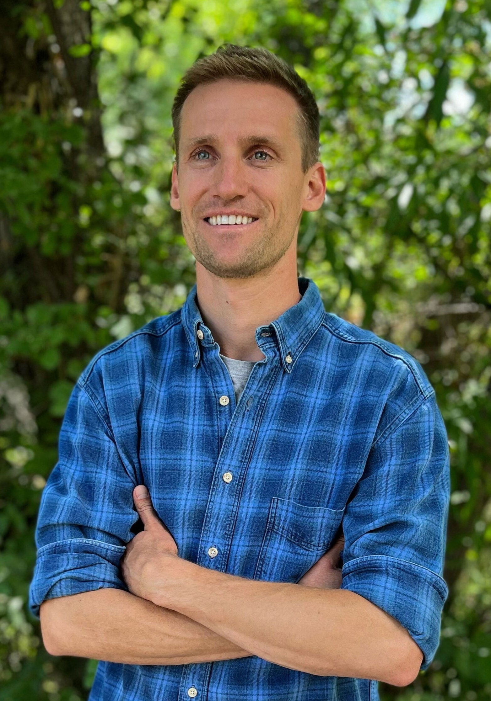 Tom Delehanty, senior attorney in Earthjustice's Rocky Mountain office, stands in front of greenery, with his arms crossed, looking off to the side.