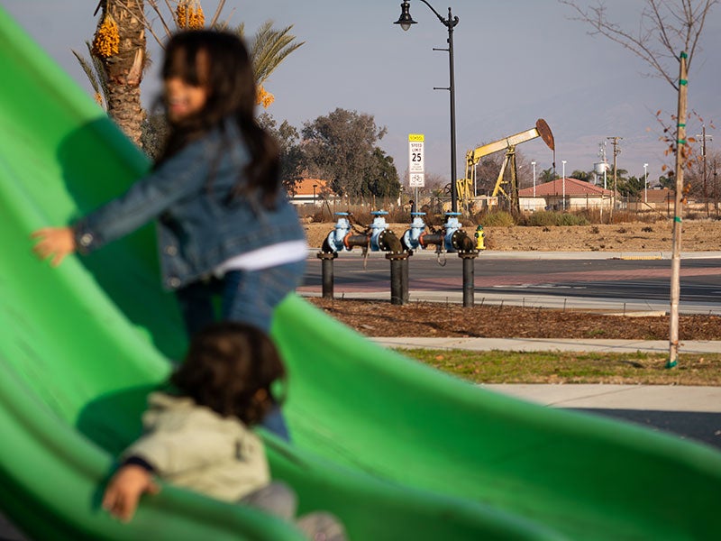 Children play at Arvin&#039;s Garden in the Sun playground in Kern County, Calif., on Jan. 3, 2021. There are several oil wells in and around the park.