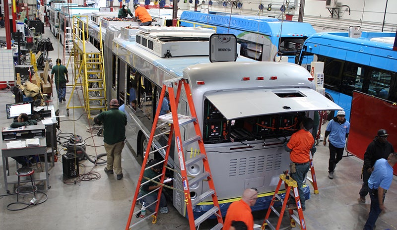 Technicians assemble an electric transit bus at a BYD facility.