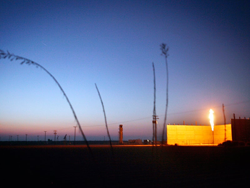 As the sun sets on another California day, a flare burns in an oil field near Bakersfield, CA.