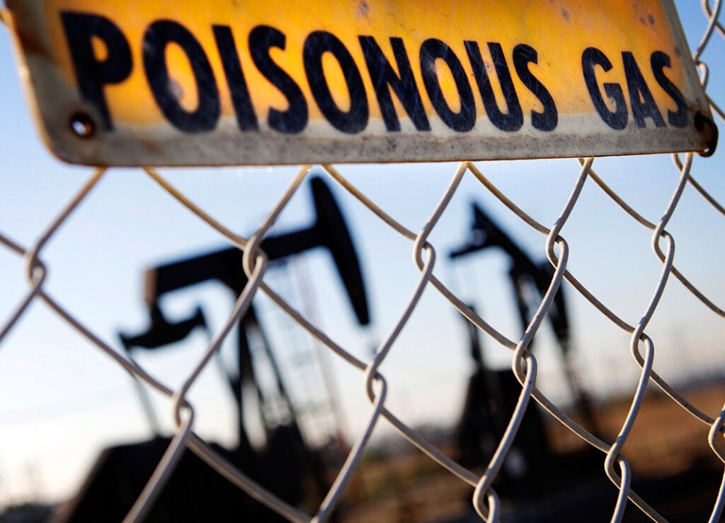 A sign hangs by an oil field in California, warning of hazardous fumes.