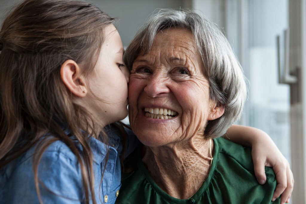 A child shares a kiss with a smiling elder.