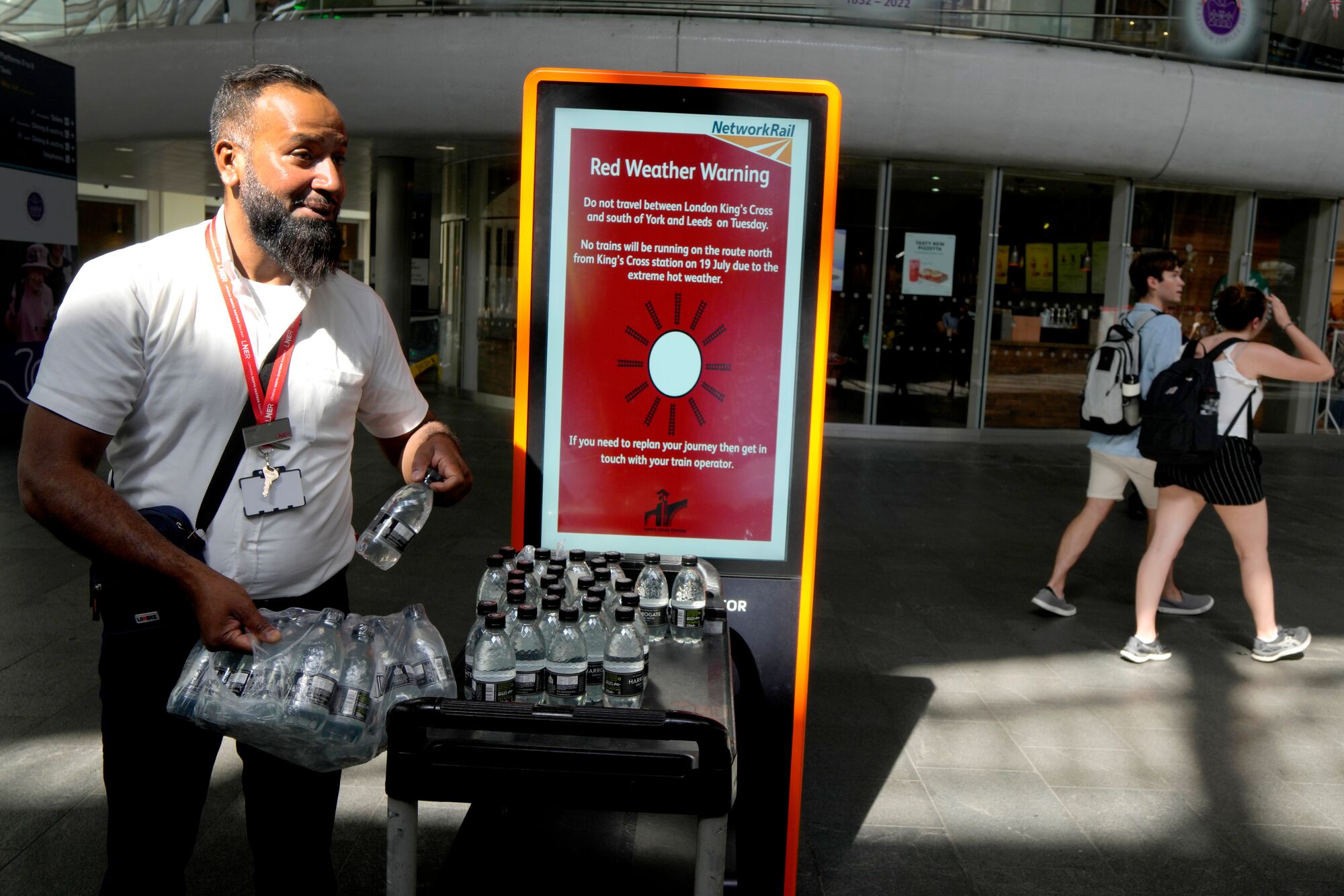 A railway worker hands out bottles of water to passengers at King's Cross railway station in London, where there were train cancellations due to the heat on July 19, 2022.