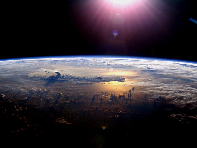 The setting of the sun over the Pacific Ocean and a towering thundercloud on July 21, 2003, as seen from the International Space Station.