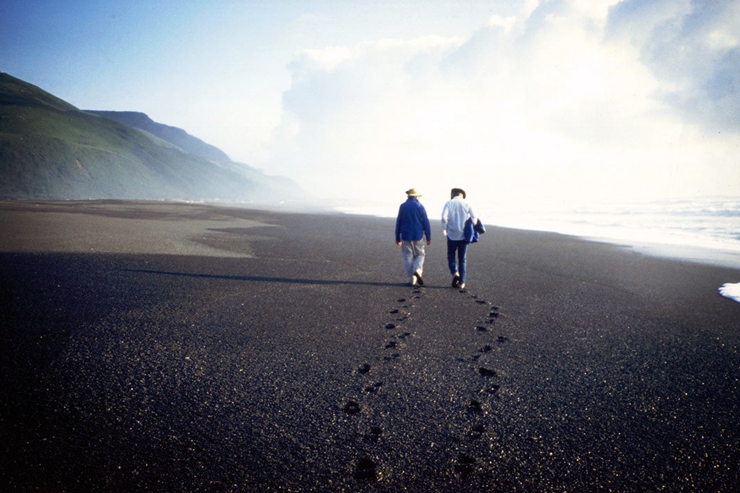 Fred Fisher and Don Harris, two of Earthjustice's co-founders, walk side-by-side on a beach.