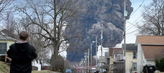 A man takes photos as a black plume rises over East Palestine, Ohio, as a result of a controlled detonation of a portion of the derailed Norfolk Southern train, Feb. 6, 2023. (Gene J. Puskar / Associated Press)