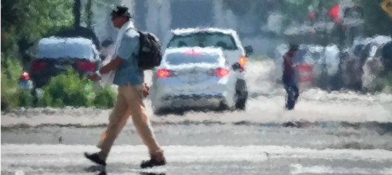 A person crosses a street in Downtown Houston in the afternoon heat in May 2024. (Jon Shapley / Houston Chronicle via Getty Images)