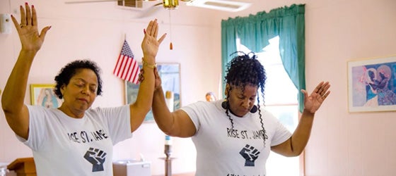 Sharon Lavigne (left) joins in a moment of prayer at a community meeting in 2019. Lavigne founded RISE St. James to expose and eliminate unchecked industrial pollution in the southern Louisiana region commonly known as Cancer Alley. (Alejandro Dávila Fragoso / Earthjustice)