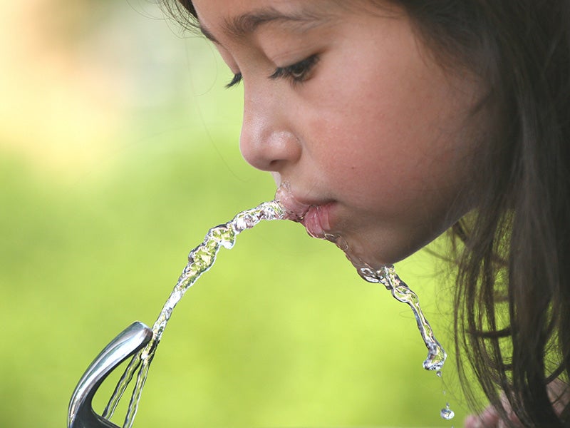 A child drinks from a water fountain.