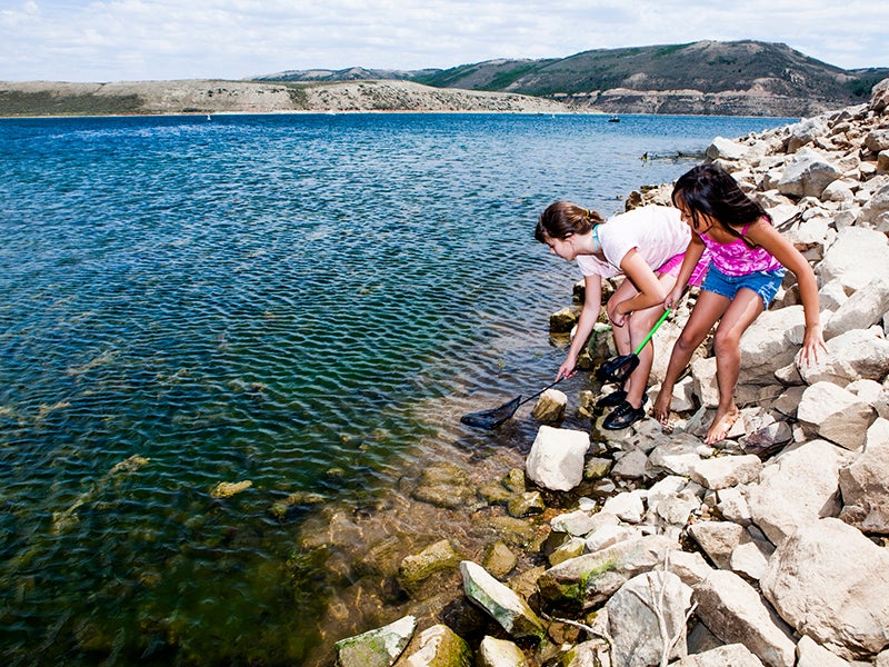 Young girls play near a river. Section 401 of the Clean Water Act empowers states and tribes to assess the impacts of federal projects on rivers, lakes, streams, and wetlands within their borders.
