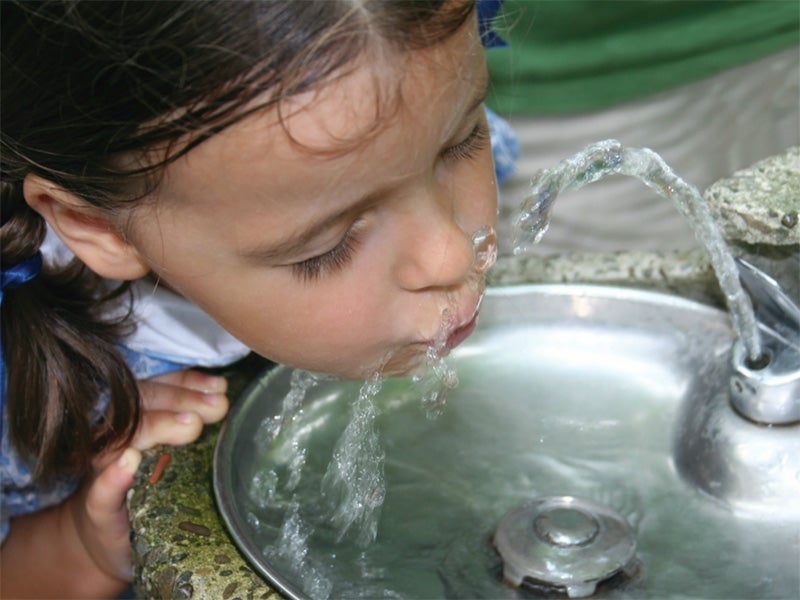 A child drinks from a water fountain.