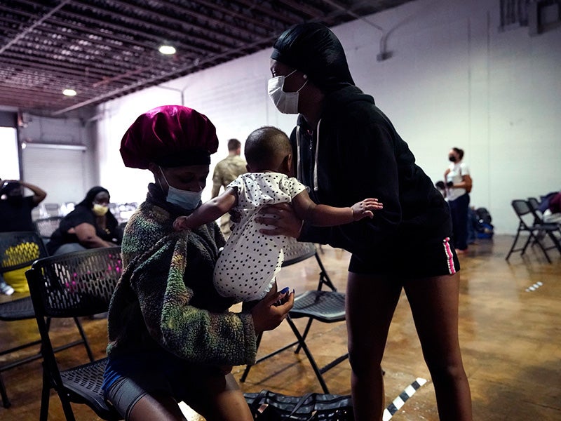 Alaira, right, reaches out to comfort her niece Delilah, 6 months, as they wait to board buses to evacuate Lake Charles, La., Aug. 26, 2020, ahead of Hurricane Laura.