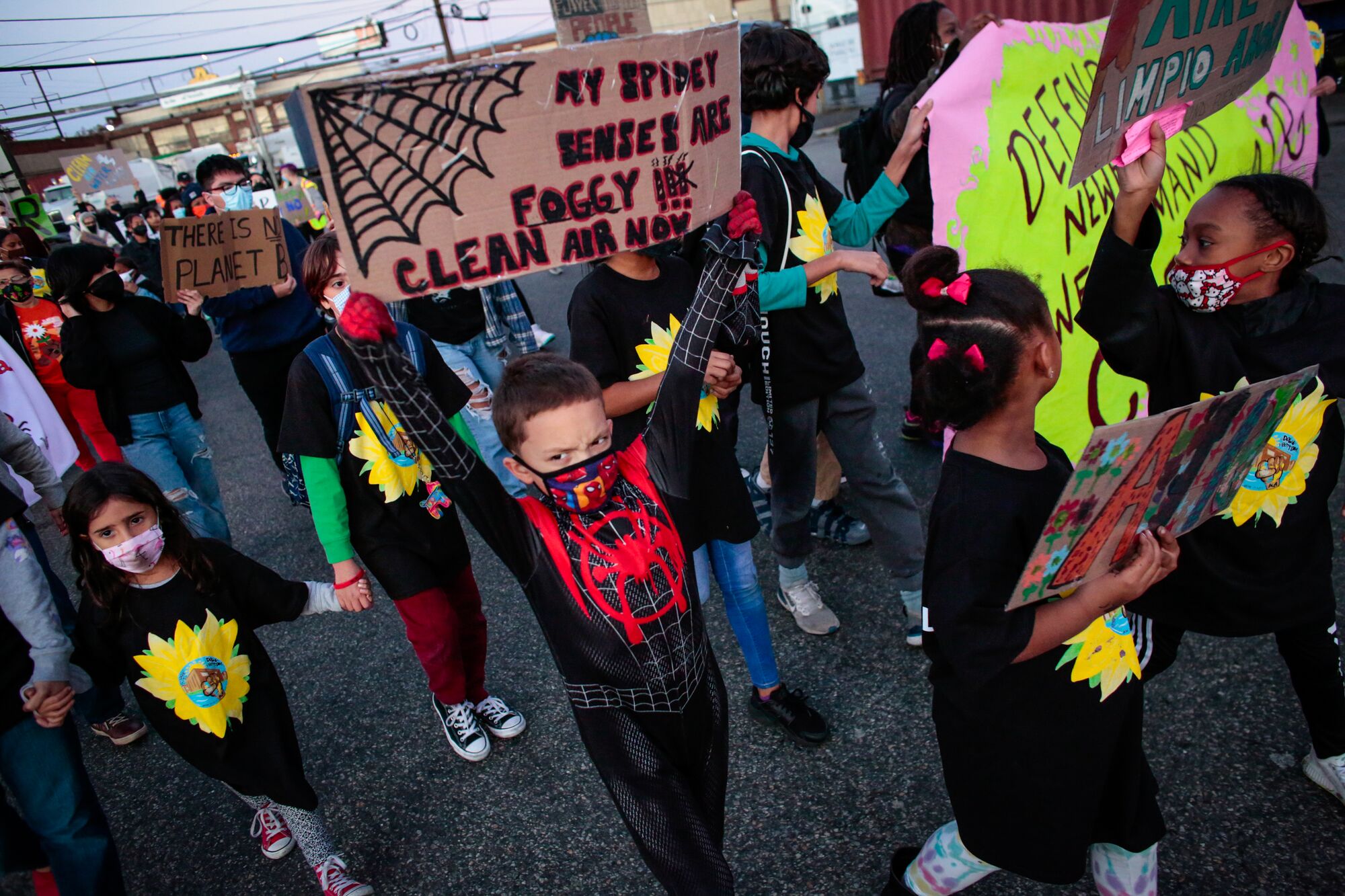 A child wearing a Spiderman mask and t-shirt marches alongside community members, while defiantly holding up a handmade poster that reads, "My spidey senses are foggy!!! Clean air now" during the "March For Clean Air! Stop Dumping in Newark" in Nov. 2021. The rally called on state officials to act against a proposed sludge facility and the extension of a gas plant in the chemical corridor area of Newark.