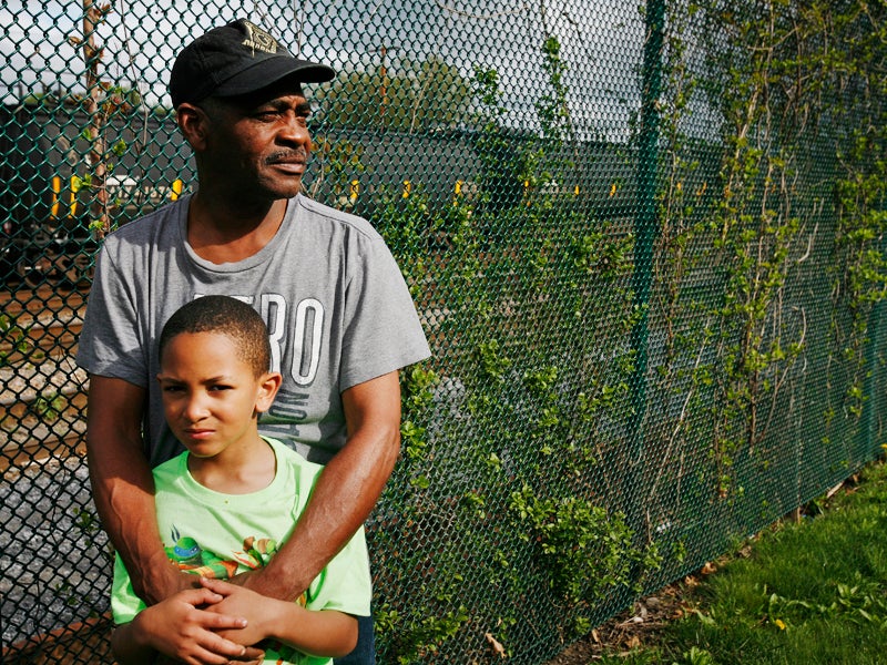 Be Be White and his son Brayton, six years old, stand along the fence that separates the railroad tracks with cars containing hazardous crude oil from Ezra Prentice Homes.
(Earthjustice Photographer)