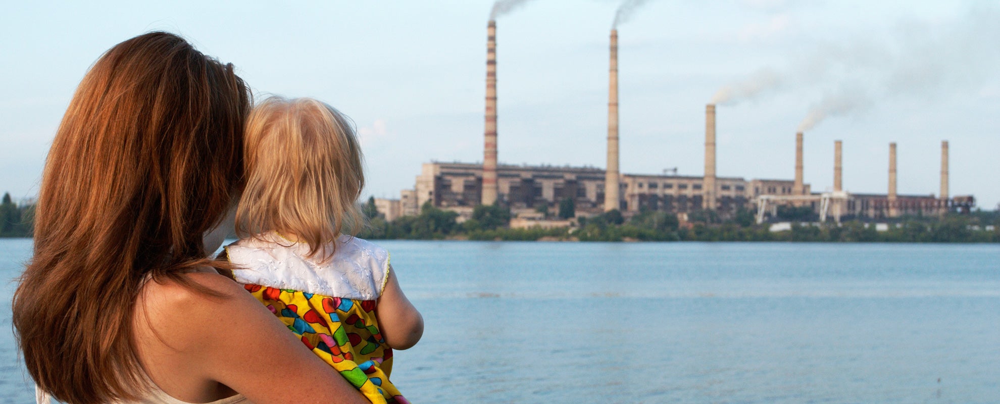 A mother and child near an industrial plant.