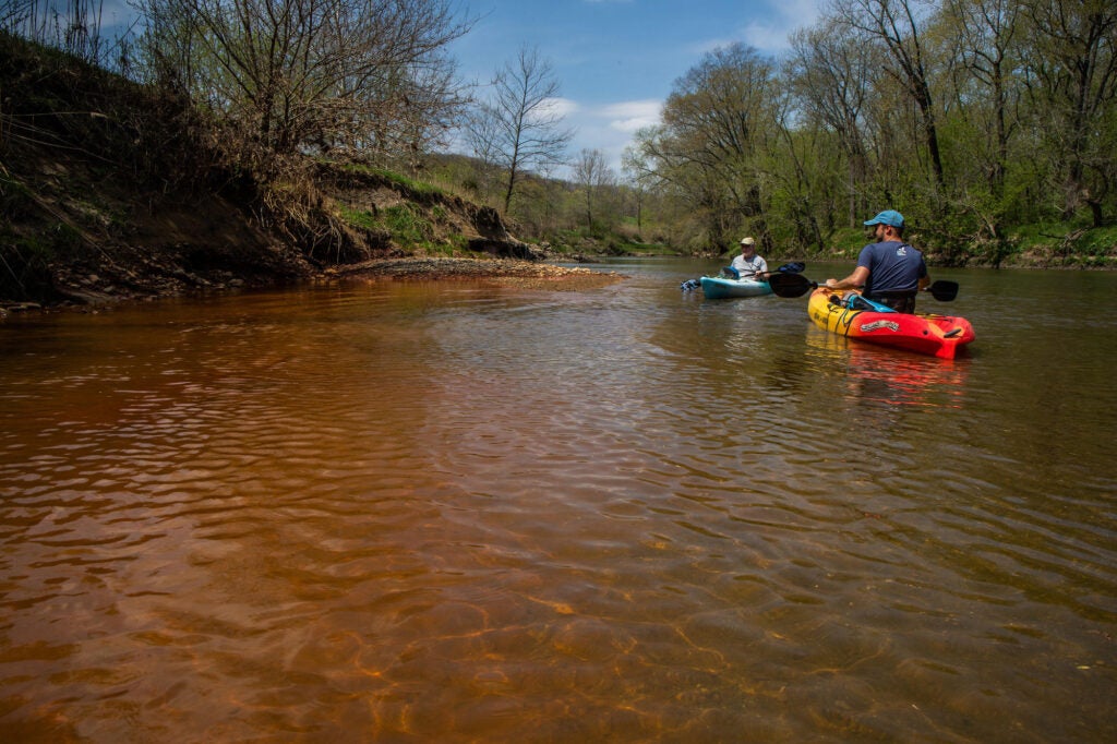 Andrew Rehn, right, of the Prairie Rivers Network and Lan Richart of Eco-Justice Collaborative paddle past toxic coal ash waste seepage on Illinois' Vermilion River in 2018. (Tribune Content Agency LLC / Alamy Stock Photo)