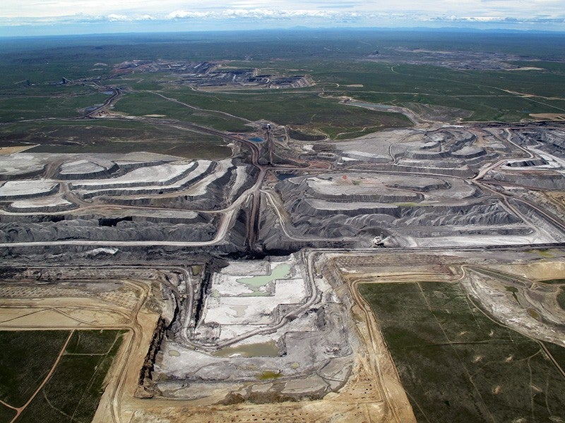 An aerial view of North Antelope Mine in Wyoming's Powder River Basin shows a deep, expansive tiered pit. The pit is so large, machinery inside the pit is dwarfed by the walls.