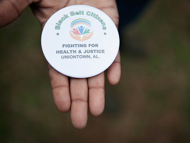 Client Esther Calhoun holds a button from the local community group fighting coal ash pollution in Uniontown, AL.