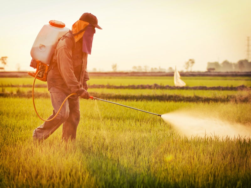 A farmer spraying a field with pesticides.