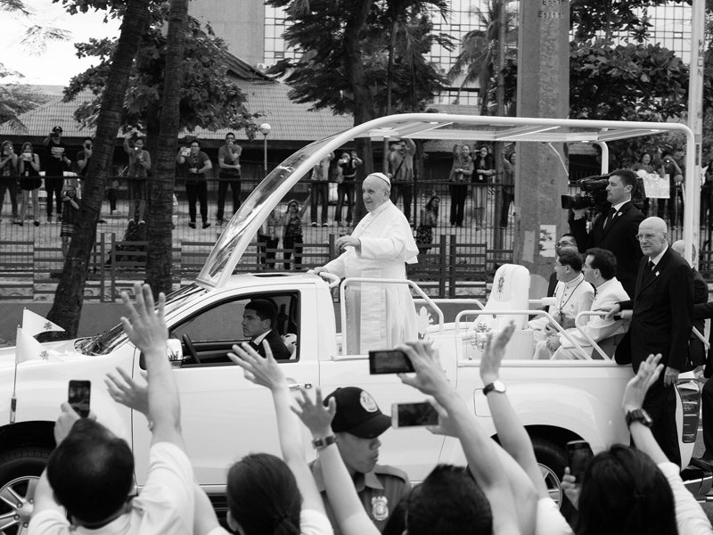 A crowd waves to Pope Francis.