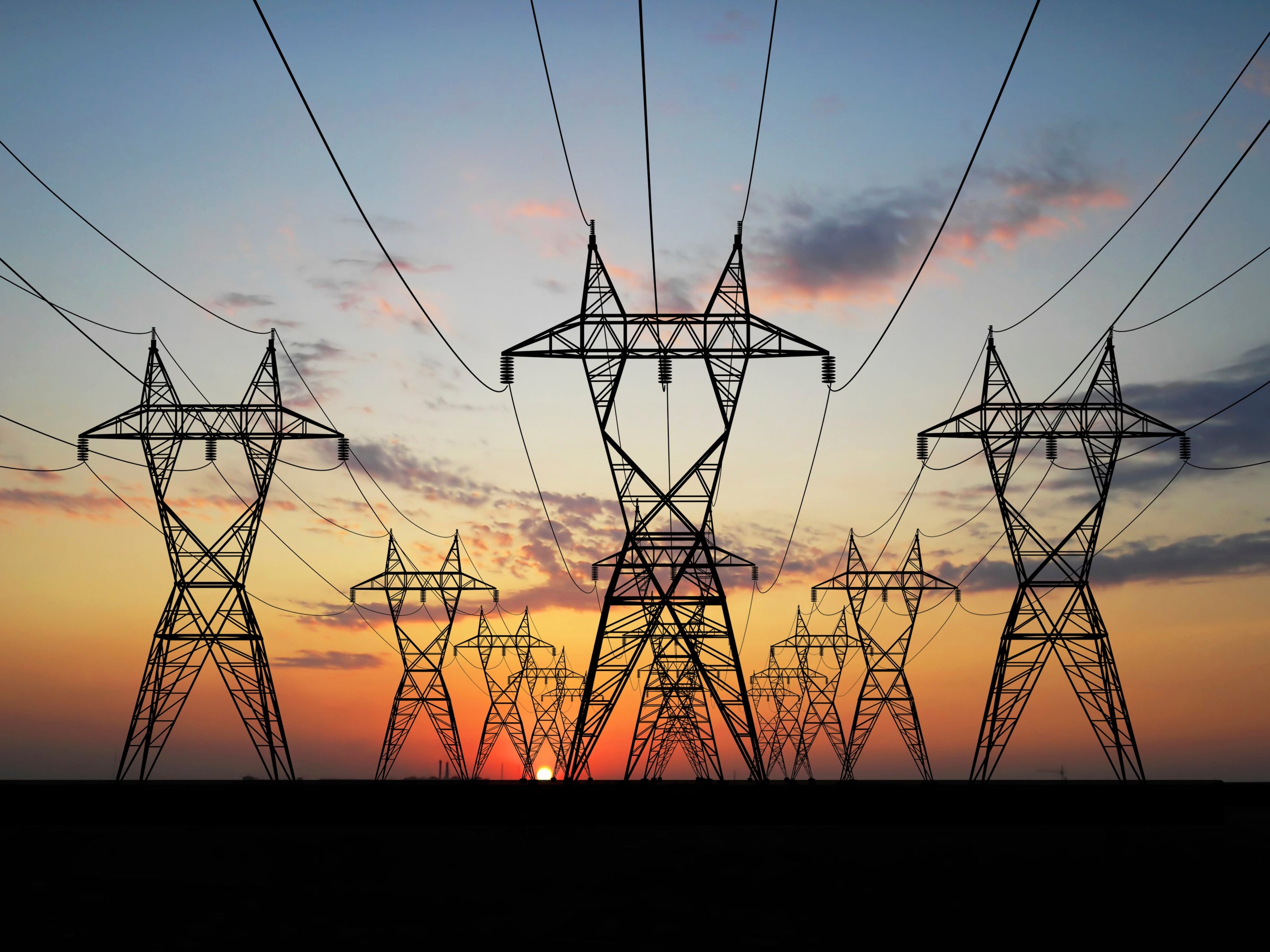 A profile of power supply lines against a sunset.