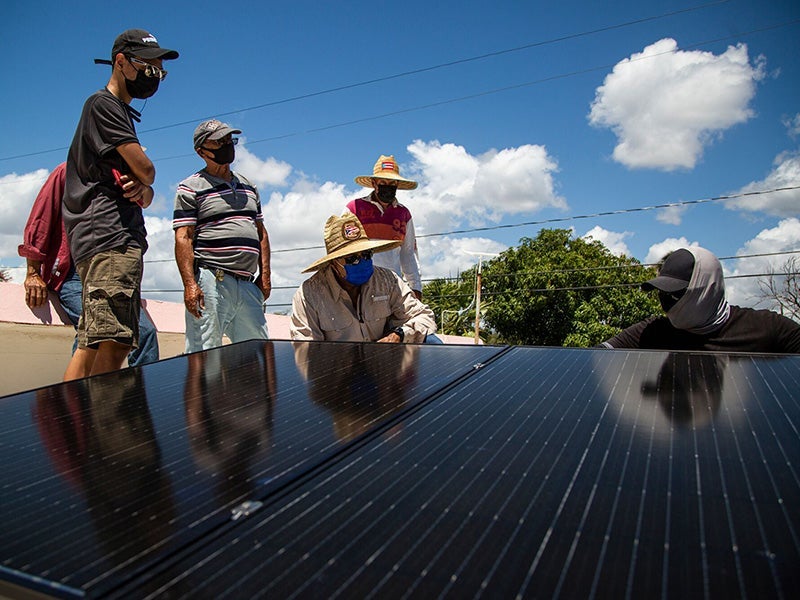 Volunteers with the group Comunidad Guayamesa Unidos por tu Salud install a solar power system in the home of community member in the Puente de Jobos neighborhood of Guayama, P.R., on Mar. 20, 2021. (Erika P. Rodríguez for Earthjustice)