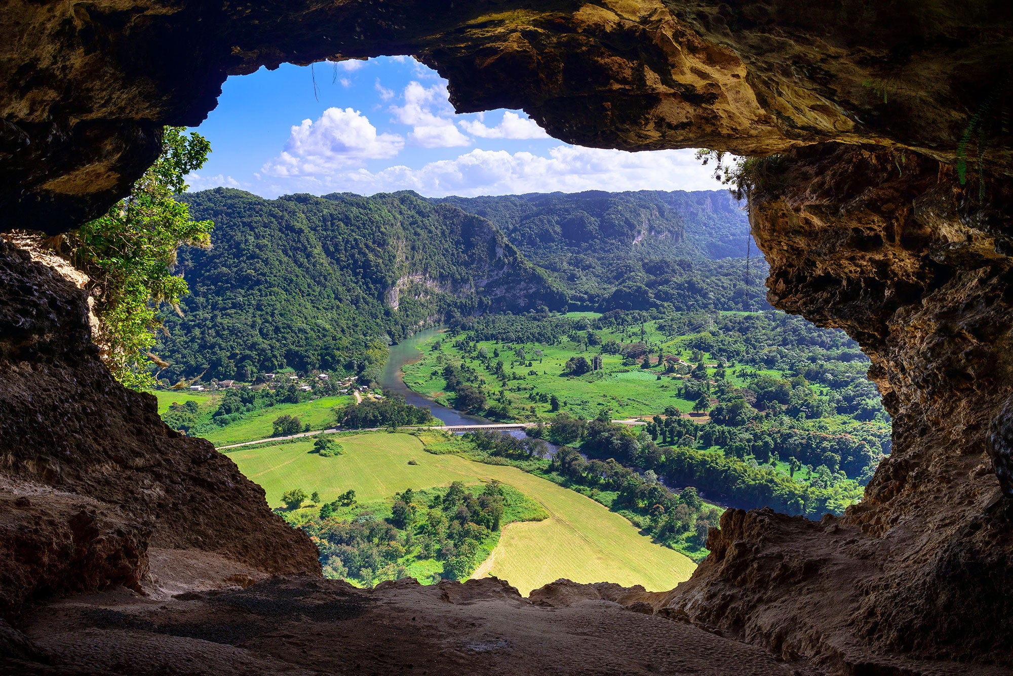 A view of the verdant landscape of Puerto Rico through an opening in the rocky mountainside.