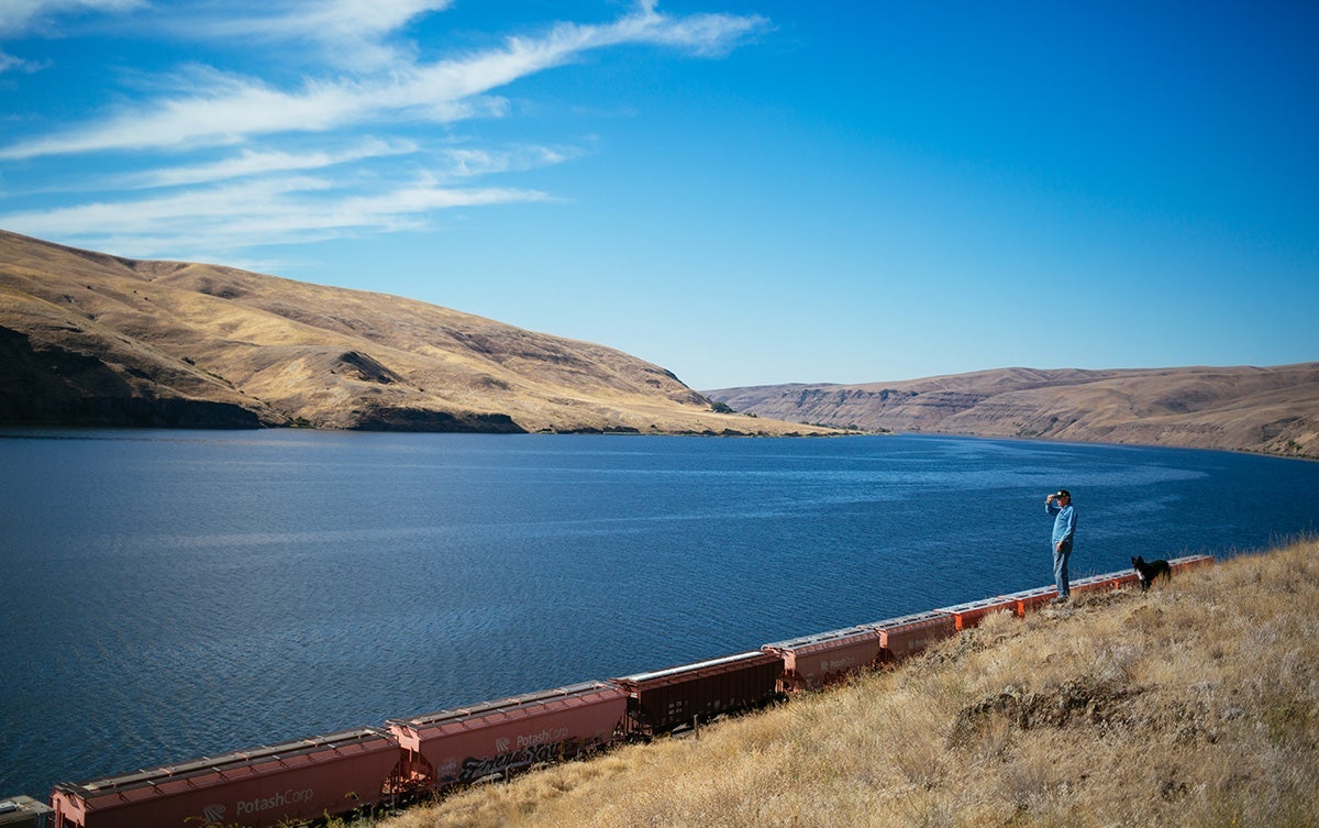 Bryan Jones, who operates one of the few family farms remaining in the community of Dusty, partway between Spokane and Clarkston, stands on a rocky outcrop above the Snake River and the railway line.