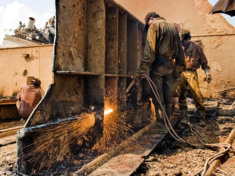 Workers breakdown a ship.