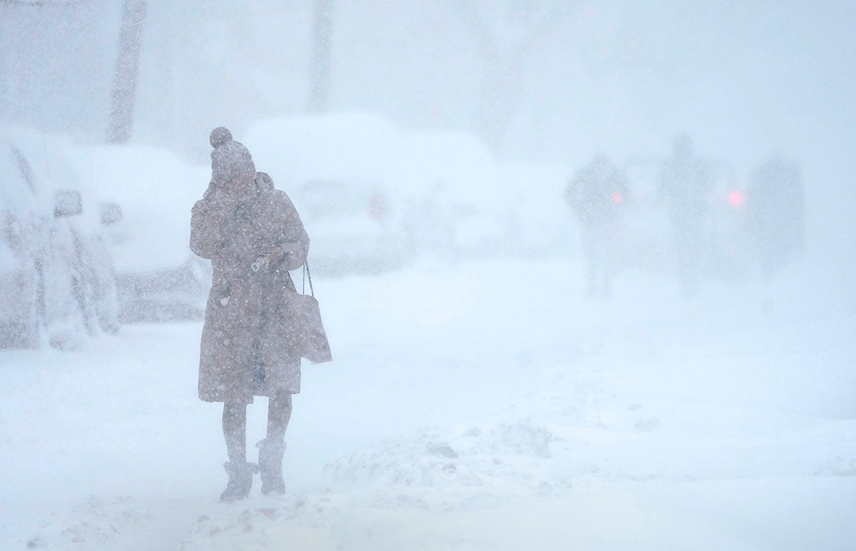 A woman tries to protect her face from blowing snow while walking in white-out conditions in Jersey City, N.J., Monday, Feb. 1, 2021. The winter storm dropped more than two feet of snow on the area and may have broken a 122-year-old snowfall record for the state.