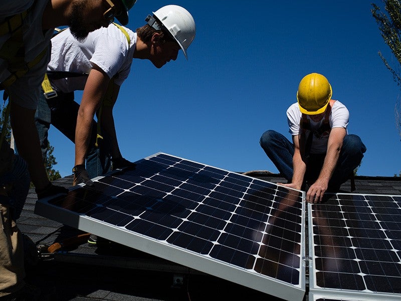 Workers install solar panels.