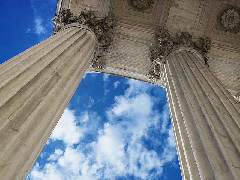 Supreme Court columns reach up toward a blue sky.