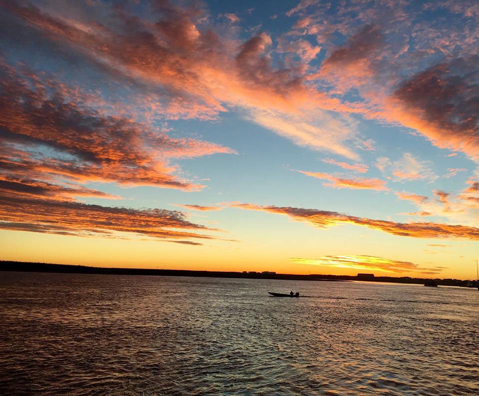 A boat in the Yukon-Kuskokwim Delta, under golden sunset colors and clouds.